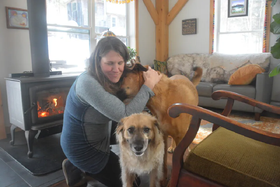 McKayla Baker hugging her dogs, Casey and Nettles, in her living room.